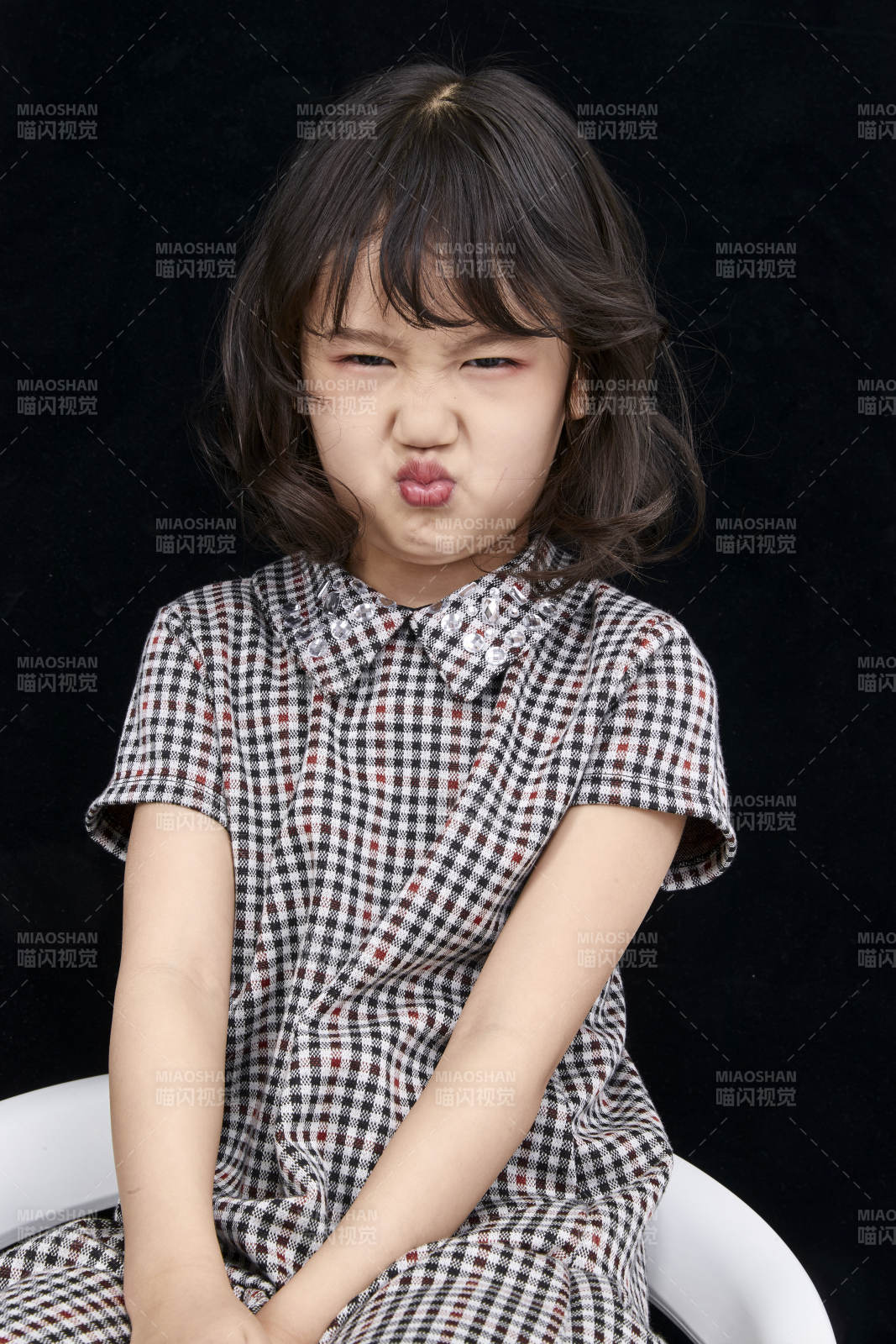 黑色背景里坐在凳子上的可愛的亞洲小女孩兒童