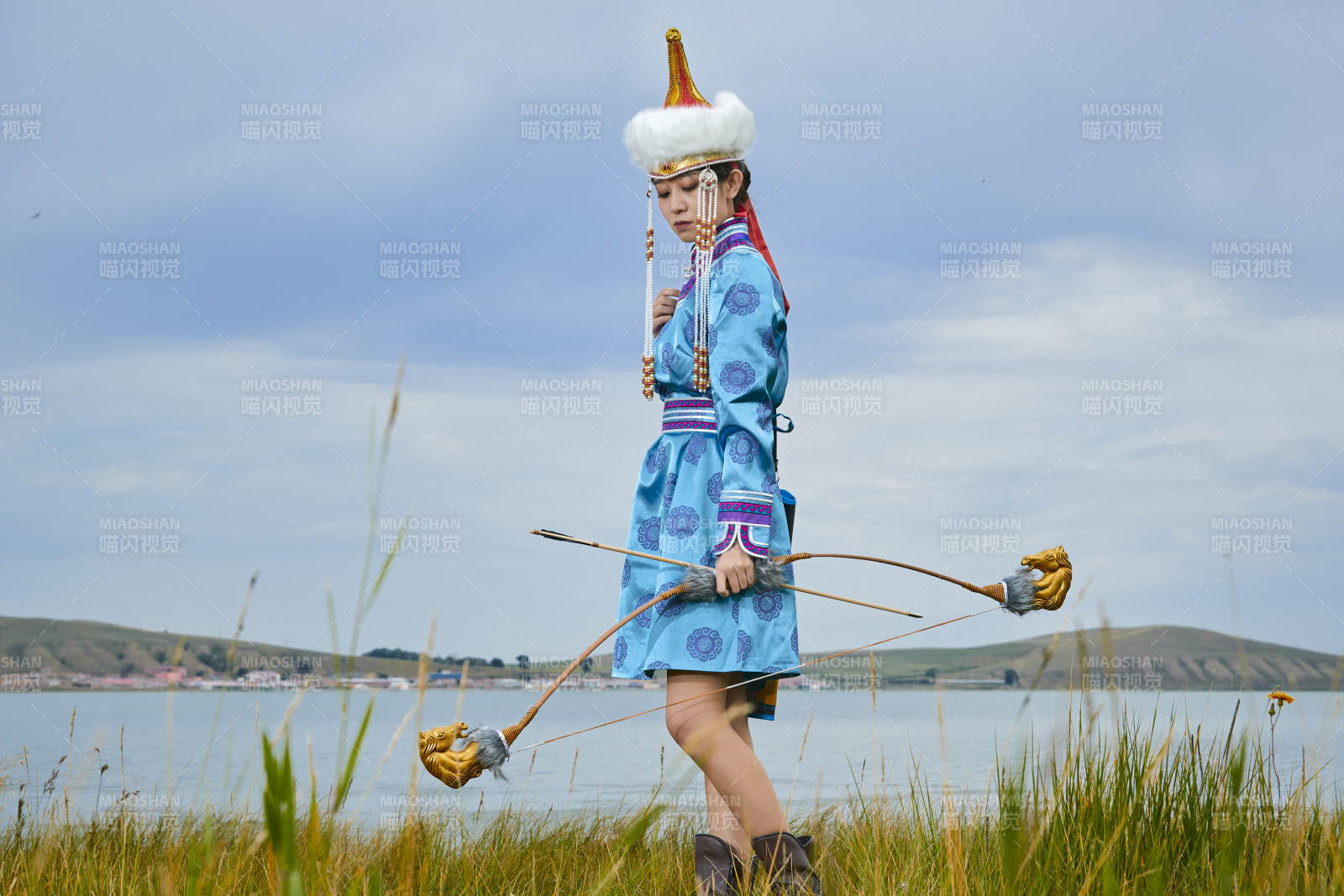 草原湖畔身穿蒙古族飾手持弓箭的蒙族少女