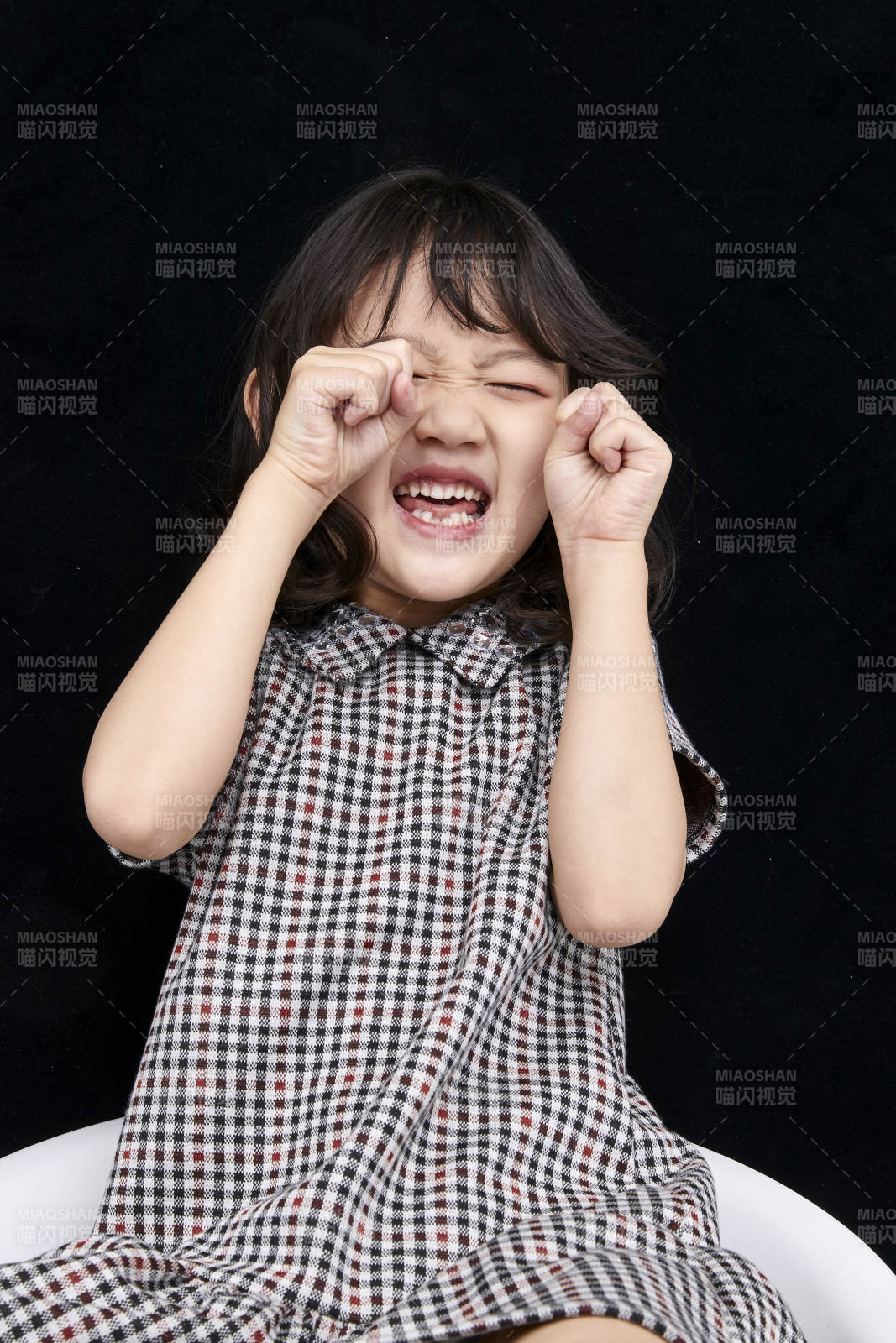 黑色背景里坐在凳子上的可愛的亞洲小女孩兒童