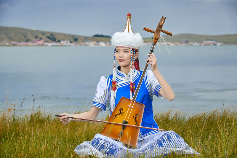 草原上穿蒙古族服饰拉马头琴的蒙族女乐手