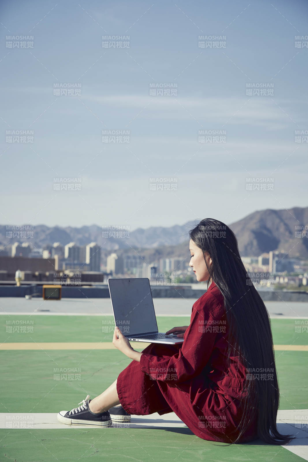 亞洲商務(wù)年輕女性在樓頂停機(jī)坪使用電腦辦公