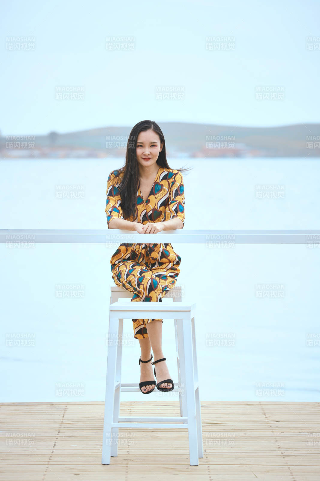 悠閑的坐在美麗湖岸碼頭的亞洲年輕女性人像