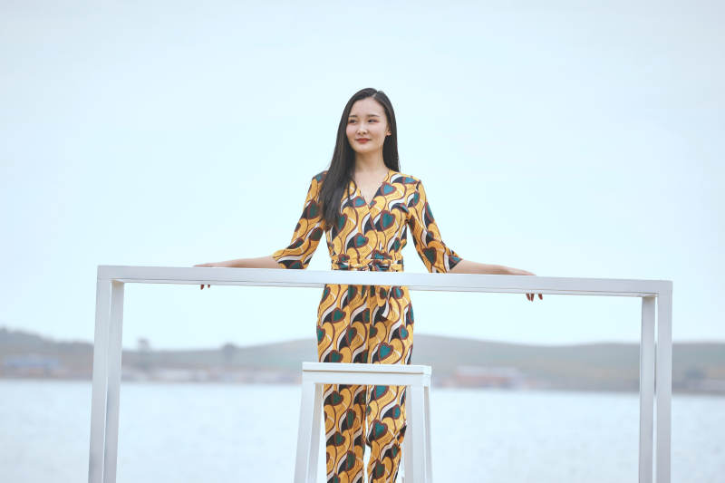 悠闲的坐在美丽湖岸码头的亚洲年轻女性人像