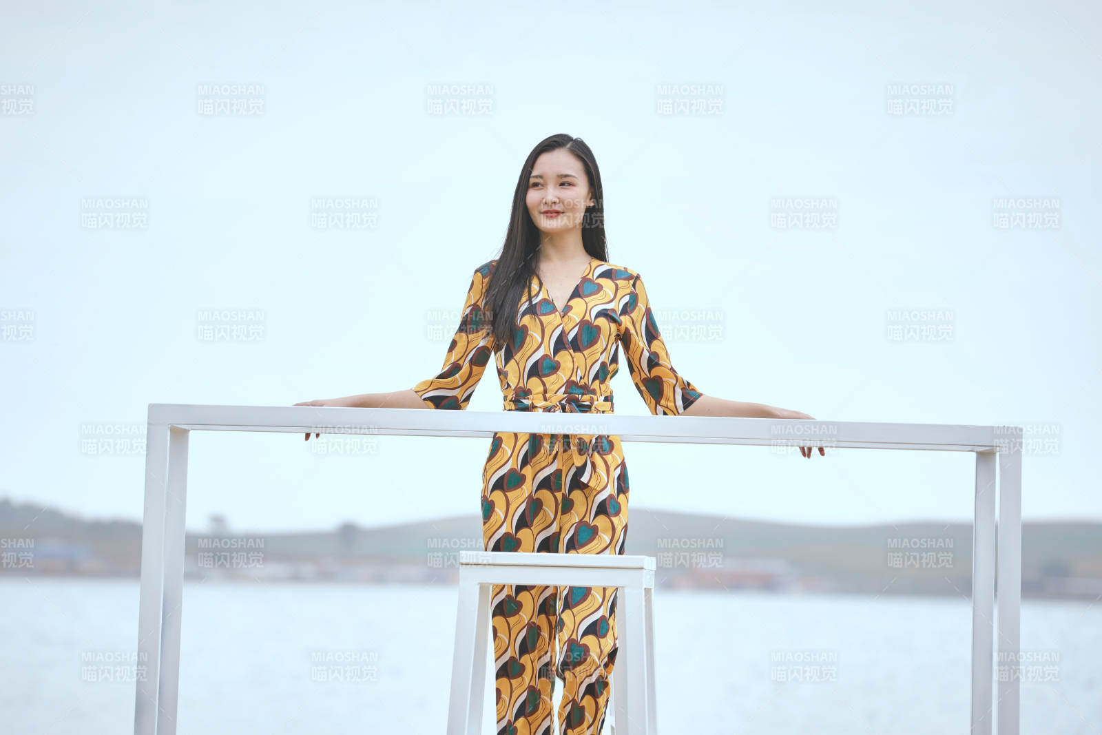 悠闲的坐在美丽湖岸码头的亚洲年轻女性人像