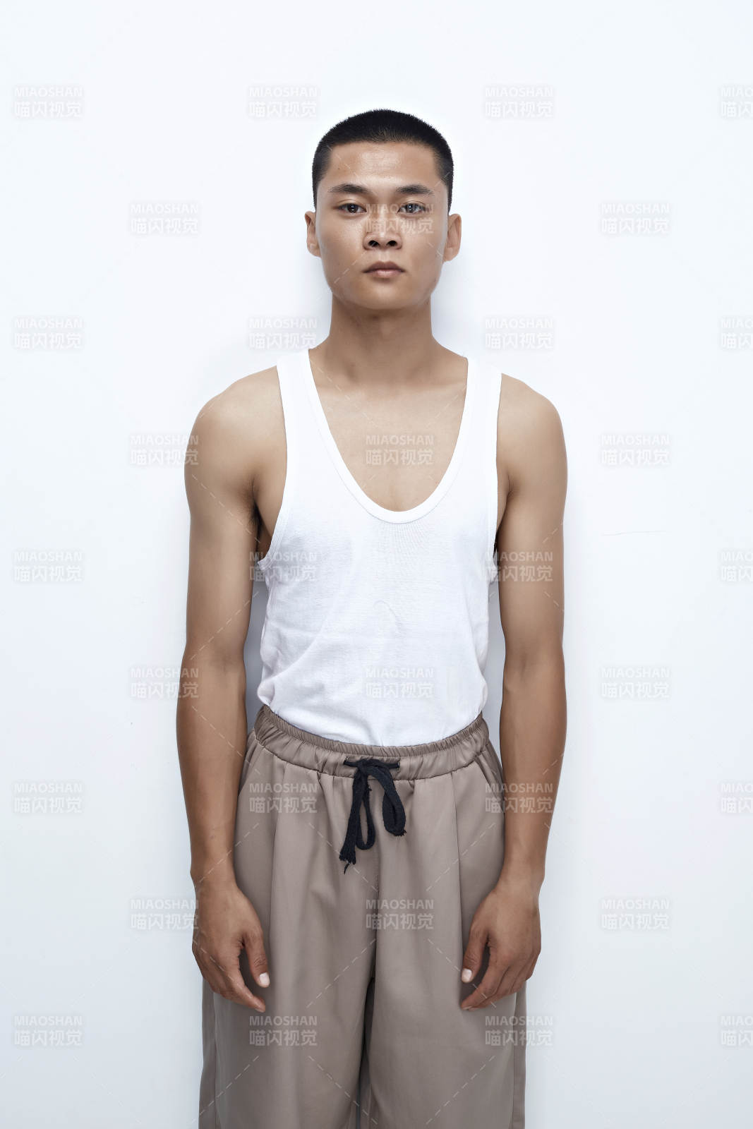 白色背景下展示健身預備拉伸動作的亞洲男性