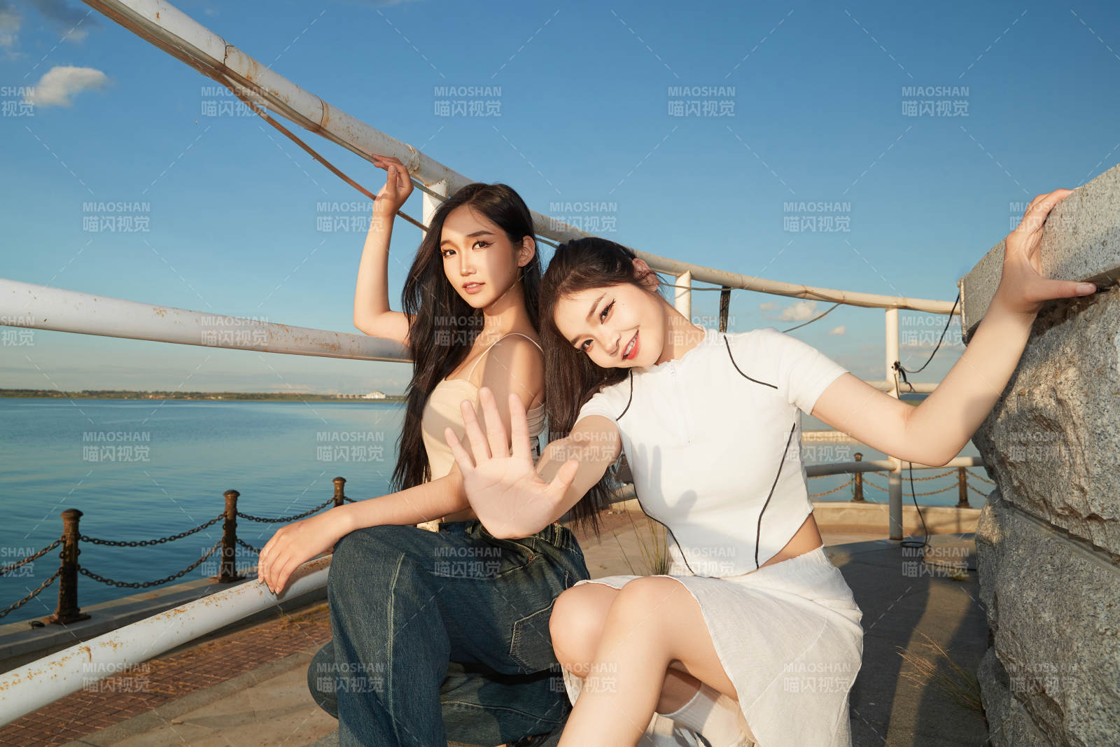 盛夏在景區湖邊燈塔上拍照游玩的美女們