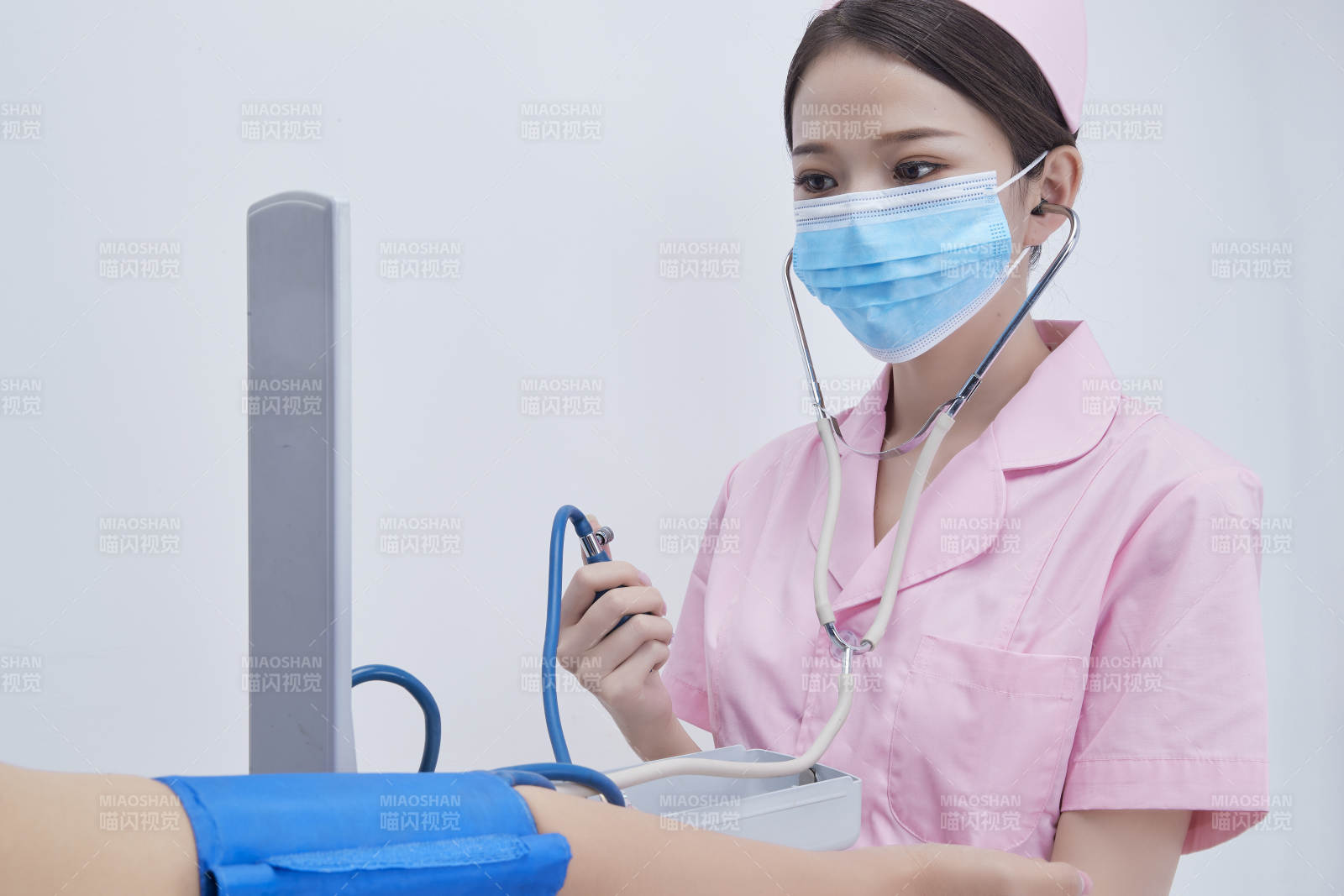 手拿血壓測量儀為患者診治量血壓的女性護(hù)士