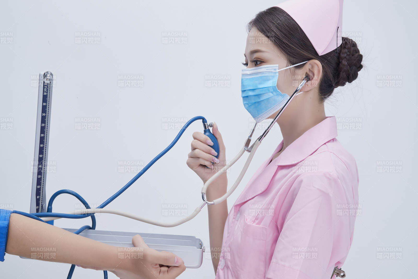 手拿血壓測(cè)量?jī)x為患者診治量血壓的女性護(hù)士