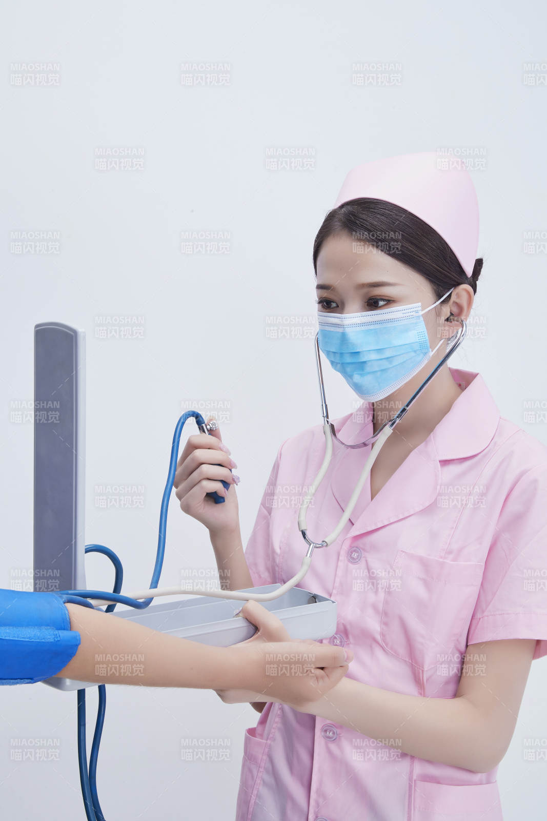 手拿血壓測量儀為患者診治量血壓的女性護士