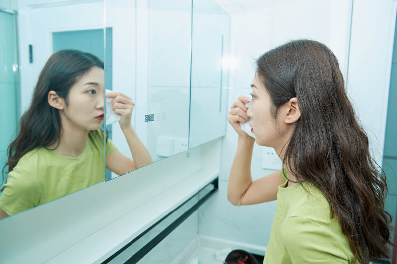 在卫生间对着镜子整理妆容的亚洲少女