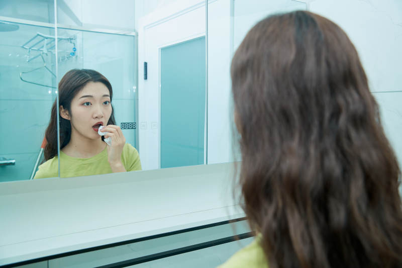 在卫生间对着镜子整理妆容的亚洲少女