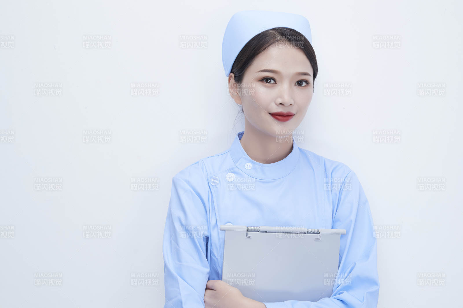 白背景里穿蓝色护士服手持病历夹的美女护士