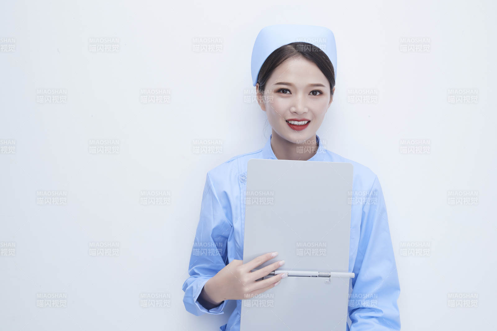 白背景里穿藍(lán)色護(hù)士服手持病歷夾的美女護(hù)士