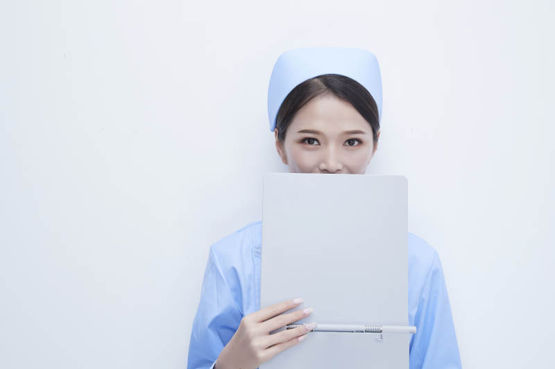 白背景里穿蓝色护士服手持病历夹的美女护士