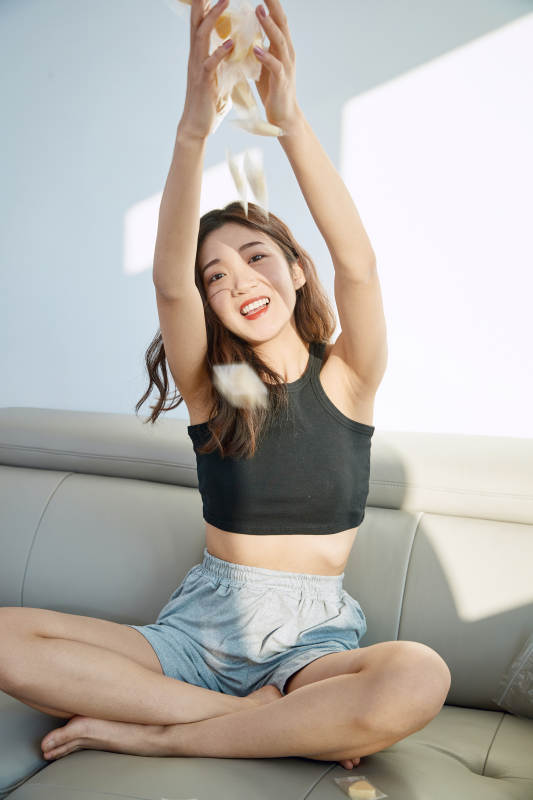 在家在沙发上享受美食的亚洲少女