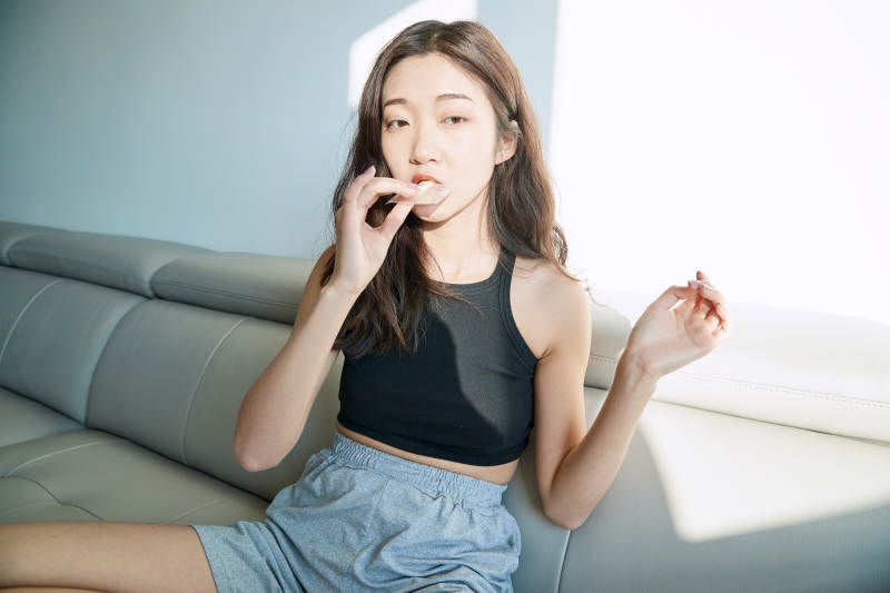 在家在沙发上享受美食的亚洲少女