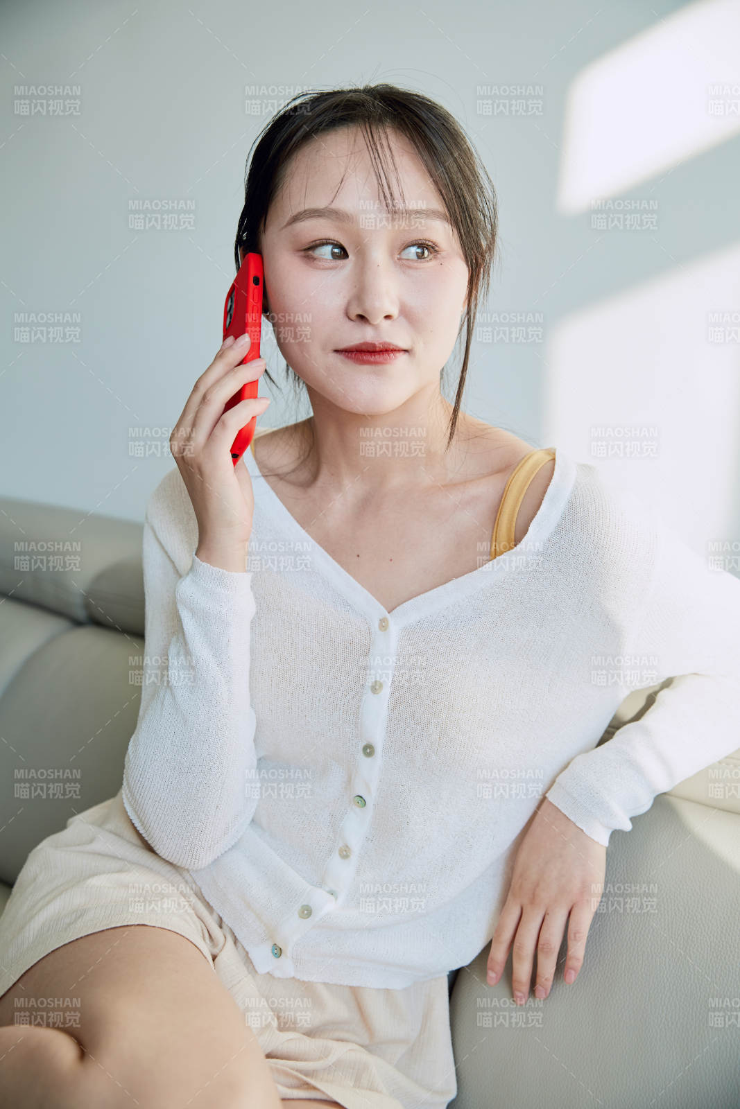 在沙發床上玩手機的年輕亞洲女性