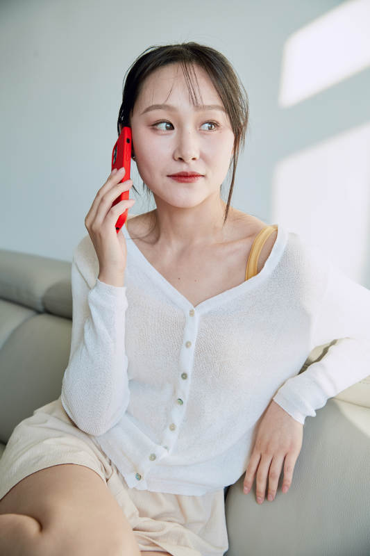 在沙发床上玩手机的年轻亚洲女性