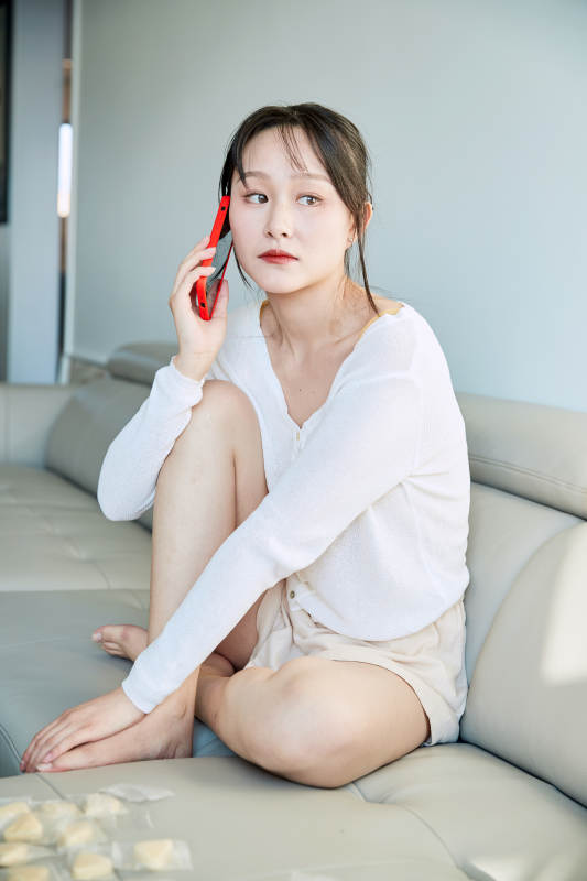 在沙发床上玩手机的年轻亚洲女性