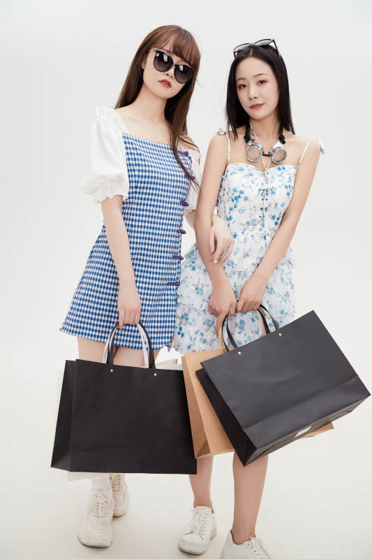 白色背景下手提购物袋时尚美丽的美女闺蜜