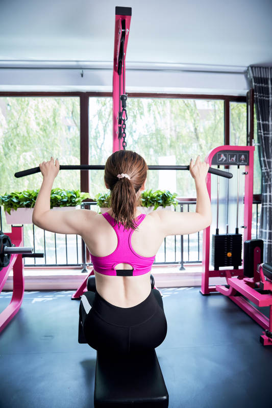 在健身房使用健身器械的亚洲女性