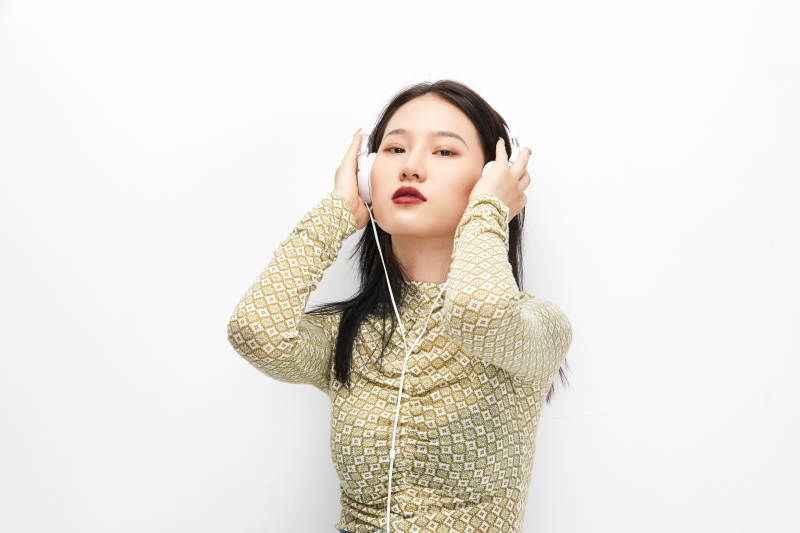 头戴耳机手持电话听音乐的少女