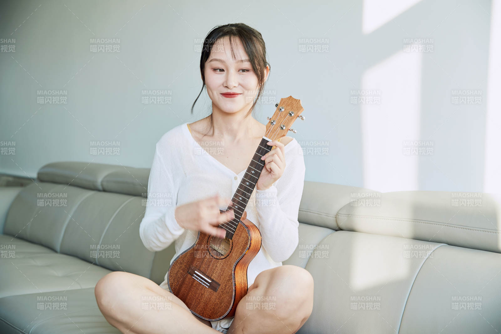 坐在沙发上弹奏尤克里里的少女