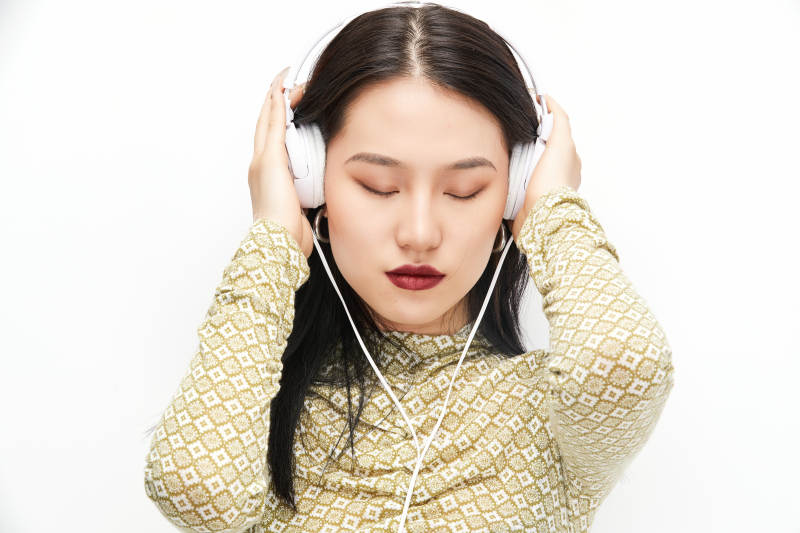 头戴耳机手持电话听音乐的少女