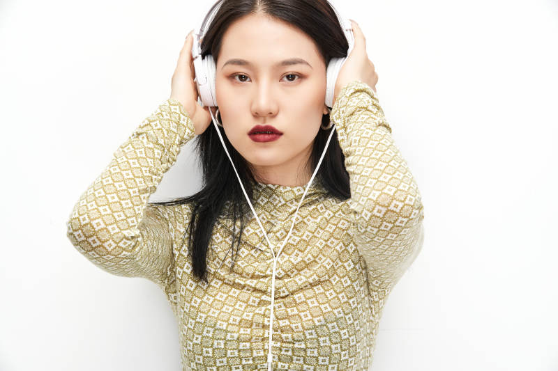 头戴耳机手持电话听音乐的少女