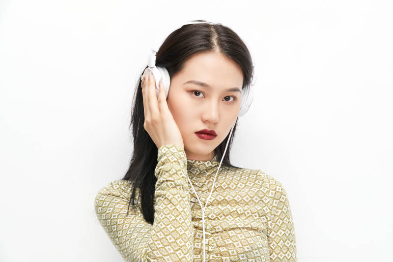 头戴耳机手持电话听音乐的少女