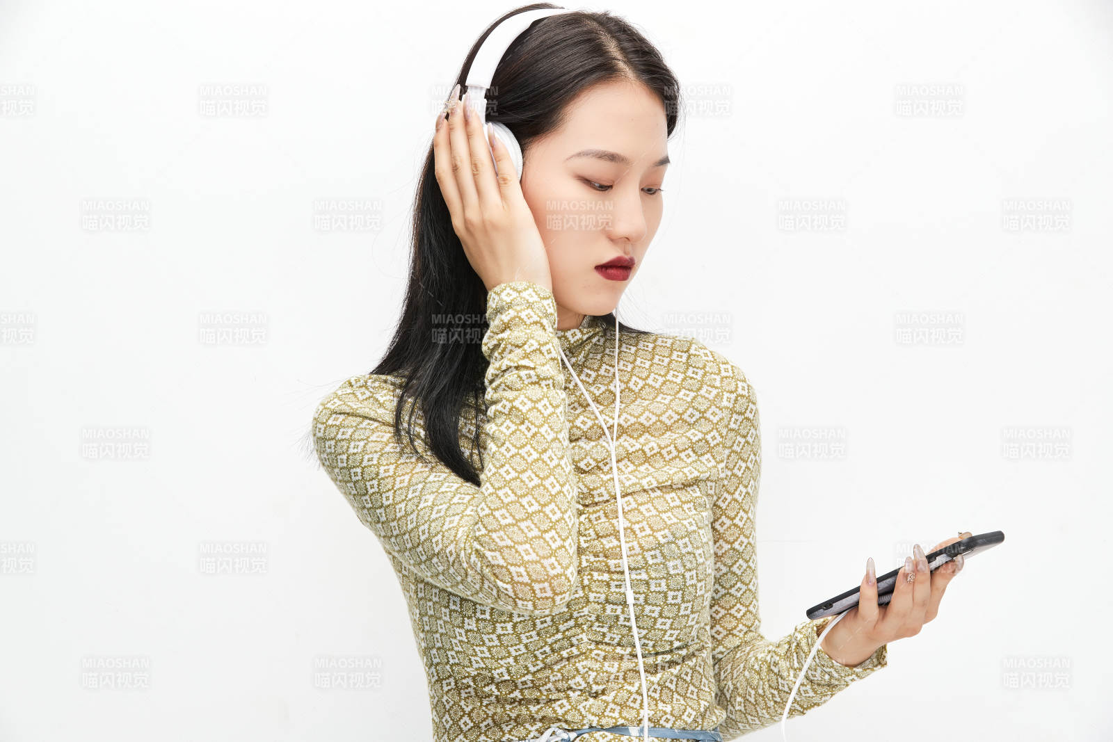 头戴耳机手持电话听音乐的少女