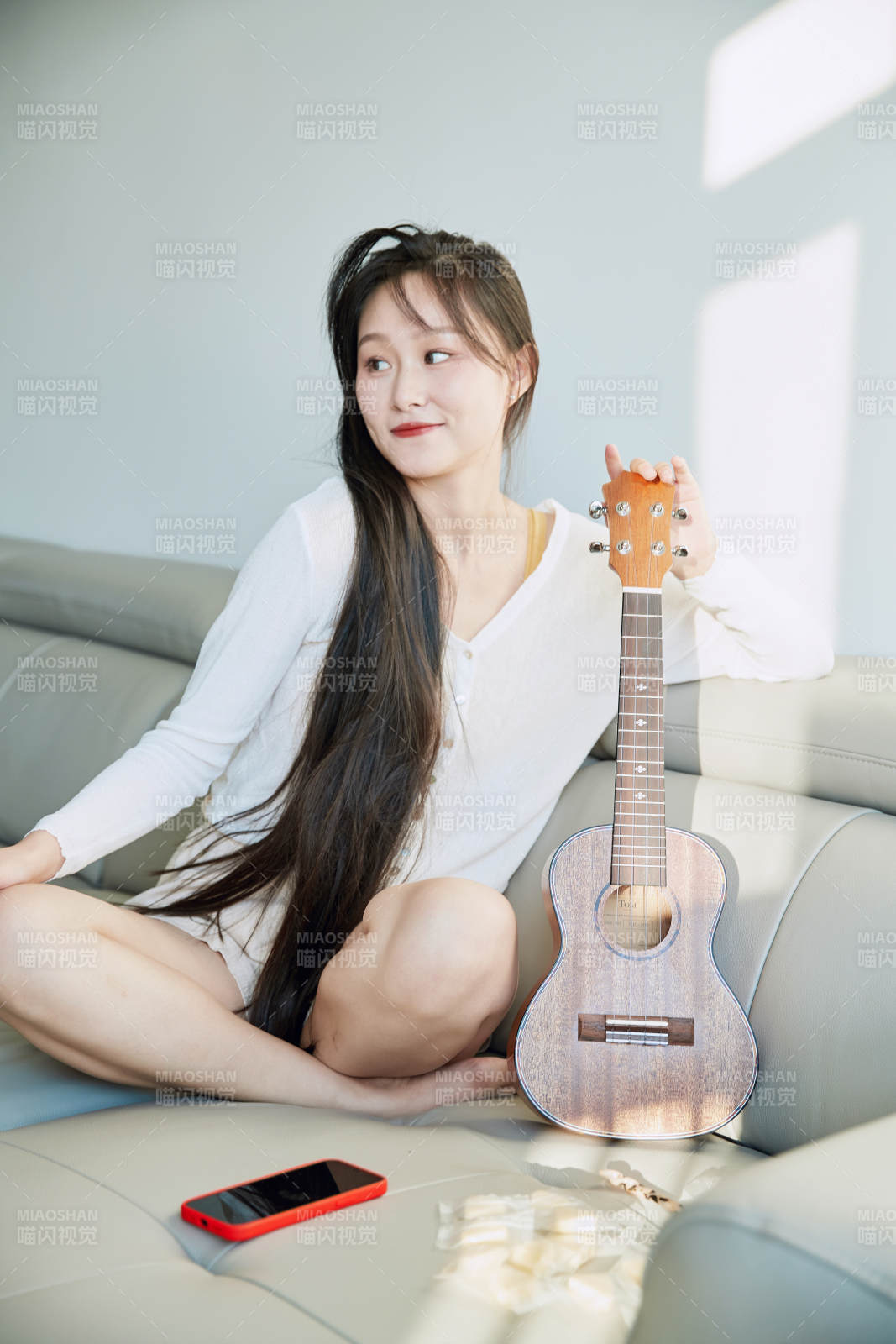 坐在沙发上弹奏尤克里里的少女