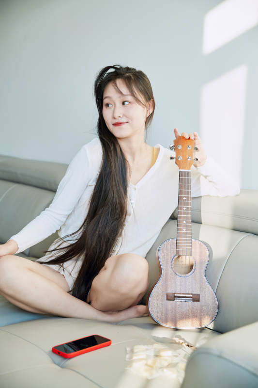 坐在沙发上弹奏尤克里里的少女