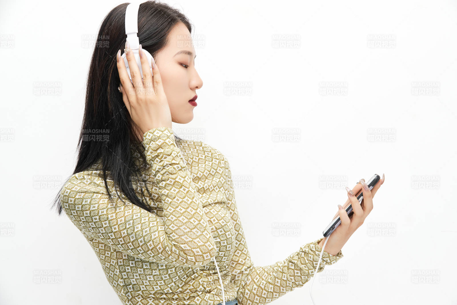 头戴耳机手持电话听音乐的少女