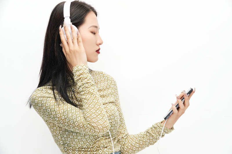 头戴耳机手持电话听音乐的少女