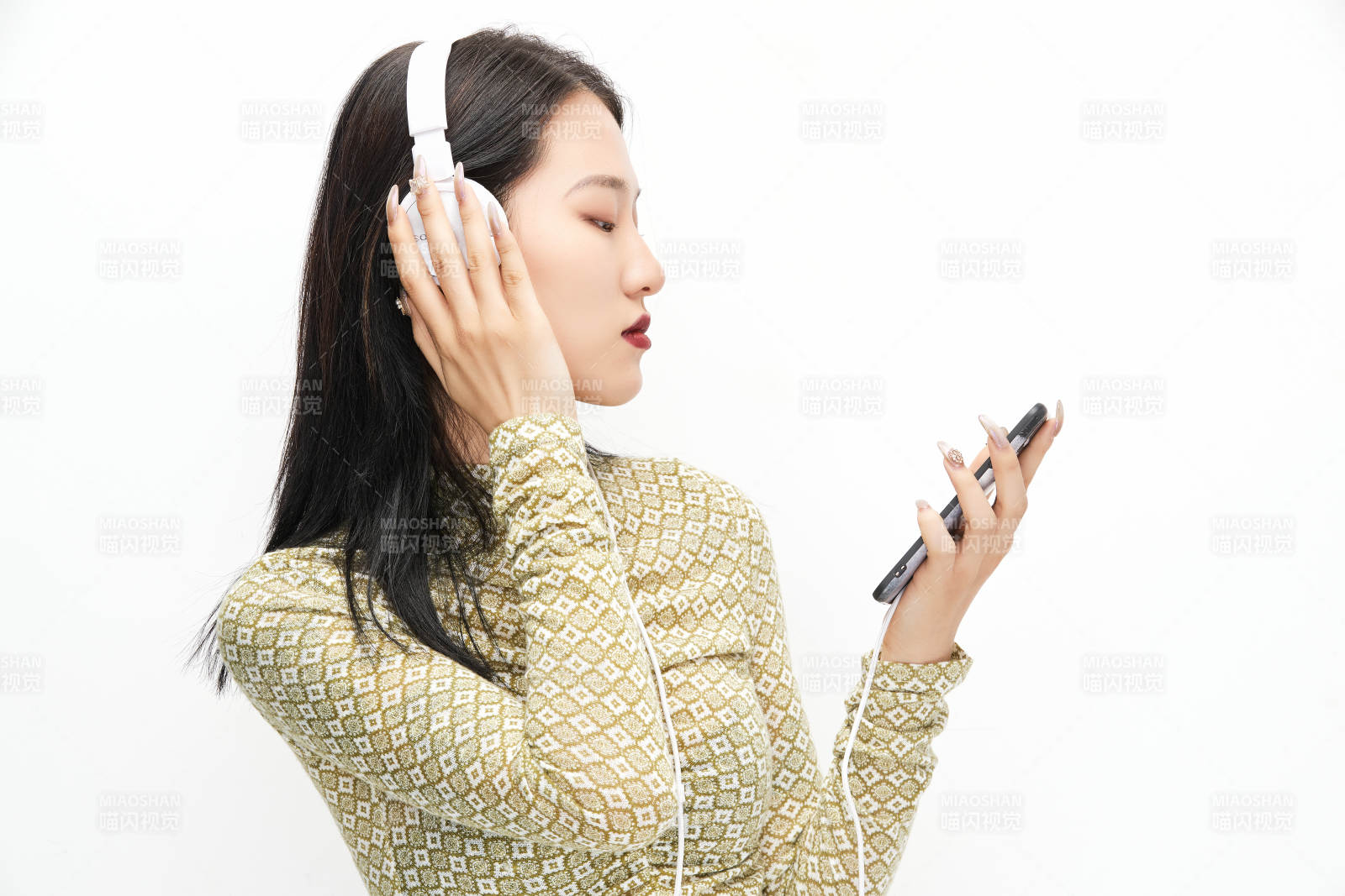 头戴耳机手持电话听音乐的少女