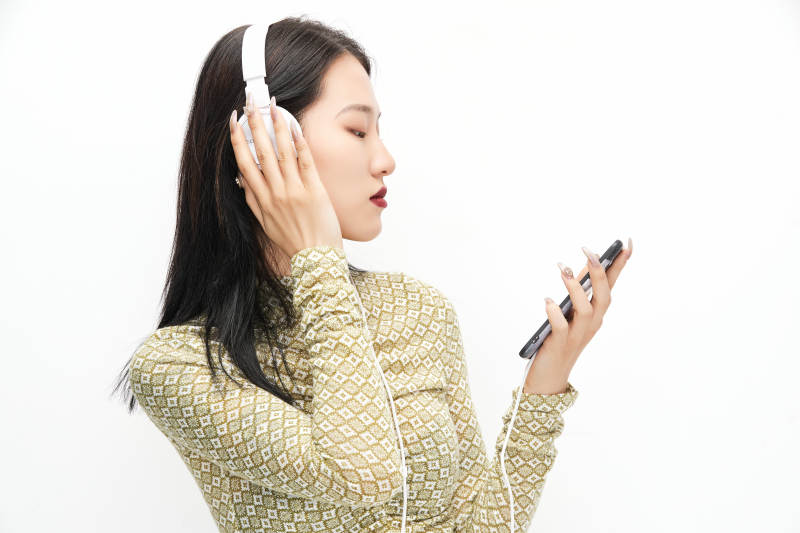头戴耳机手持电话听音乐的少女