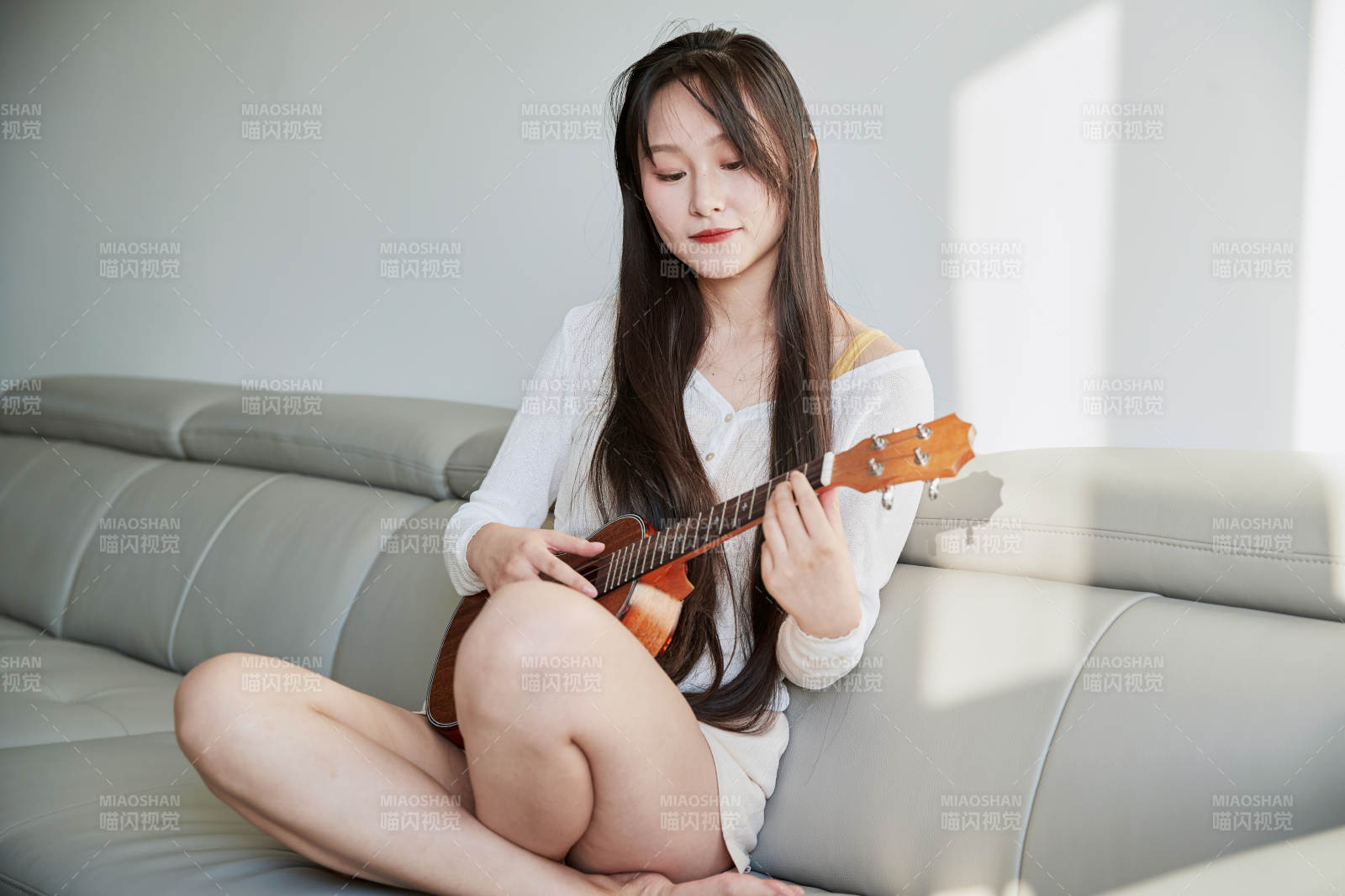 坐在沙发上弹奏尤克里里的少女