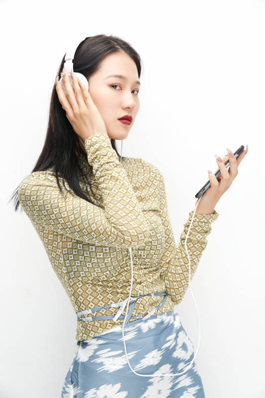 头戴耳机手持电话听音乐的少女