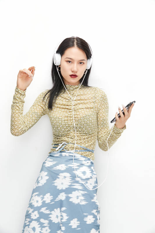 头戴耳机手持电话听音乐的少女