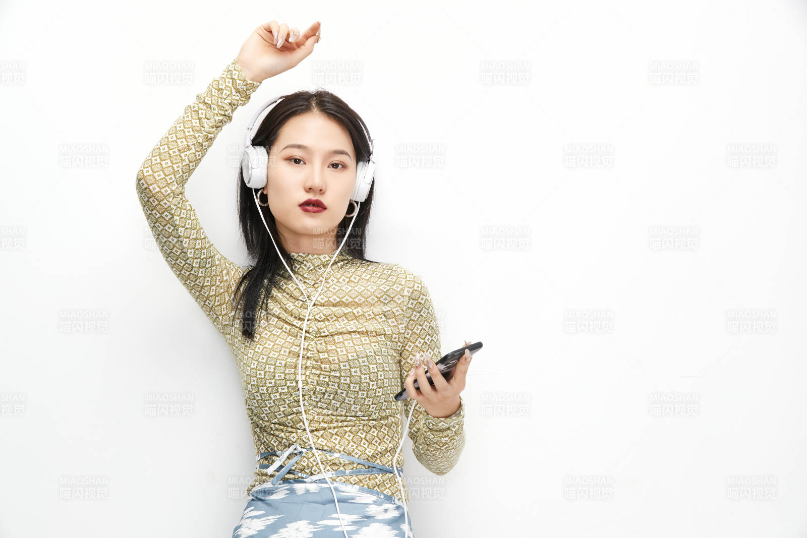 頭戴耳機手持電話聽音樂的少女