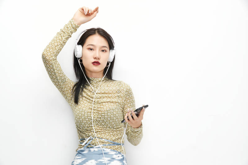 頭戴耳機手持電話聽音樂的少女