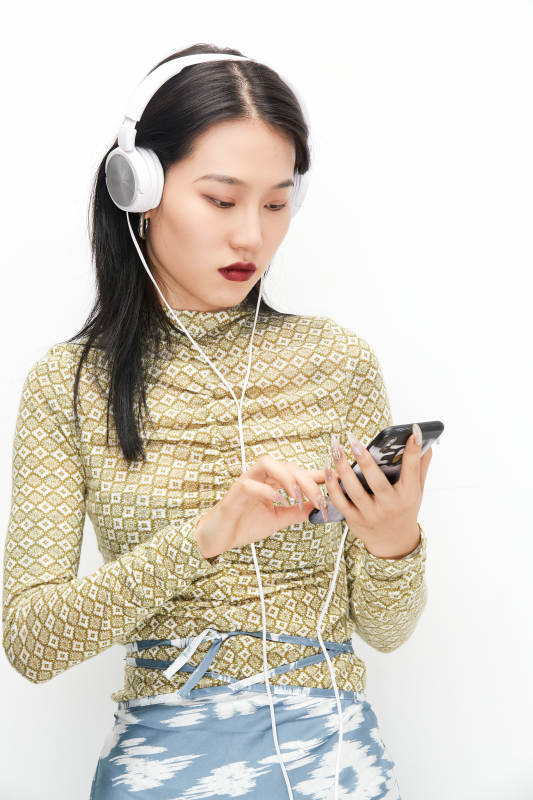 头戴耳机手持电话听音乐的少女