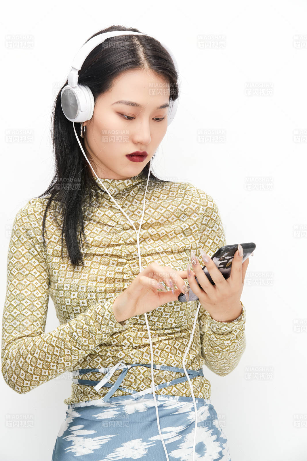 头戴耳机手持电话听音乐的少女