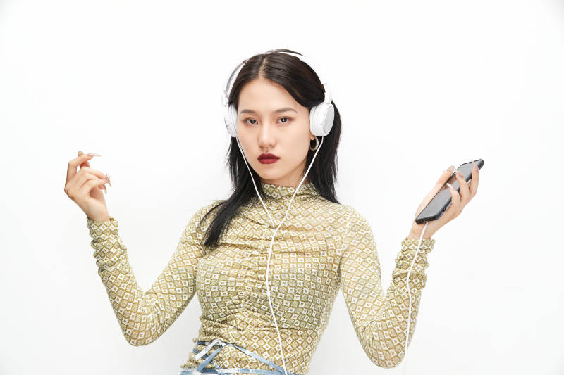 头戴耳机手持电话听音乐的少女