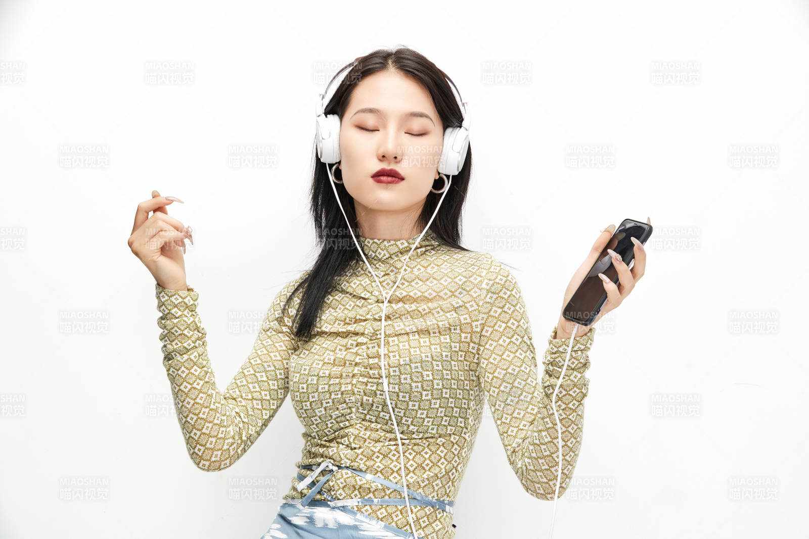 头戴耳机手持电话听音乐的少女