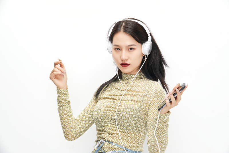 頭戴耳機手持電話聽音樂的少女