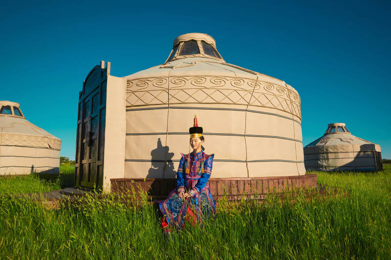 夕阳下草原蒙古大帐前穿蒙族服饰的美女