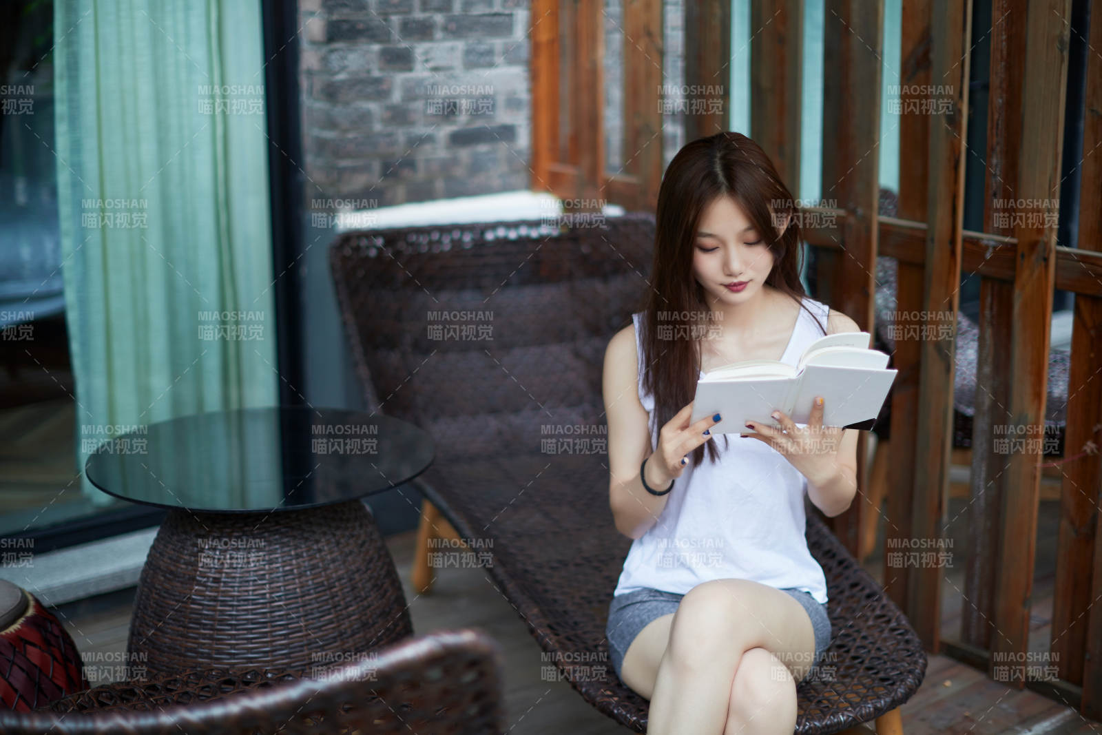 院子里坐在长椅上阅读书籍的亚洲长发少女