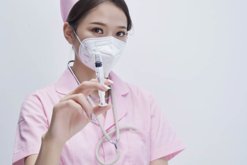 穿护士服戴听诊器口罩手执针筒的年轻女护士